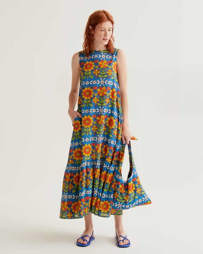 Woman wearing a colorful floral dress holding a matching bag on a white background