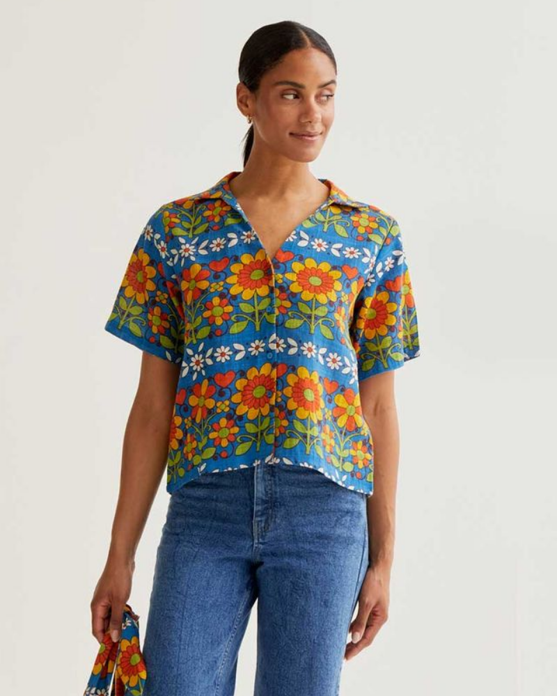 Woman wearing a colorful floral shirt with a plain background