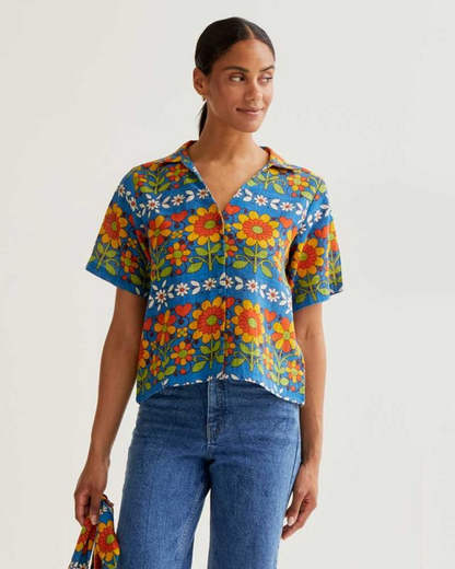 Woman wearing a colorful floral shirt with a plain background