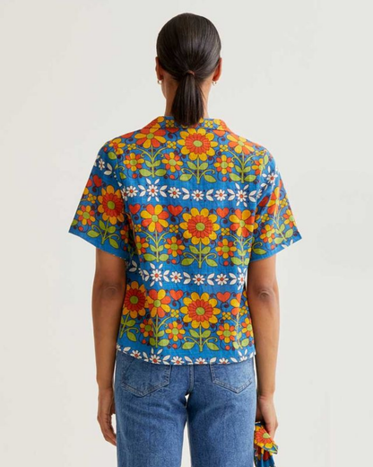 Person wearing a colorful floral patterned shirt on a plain background