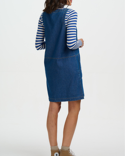Person wearing a blue denim dress over a striped shirt on a white background
