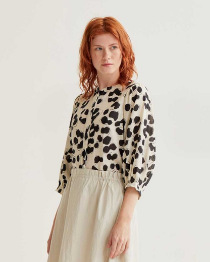 Woman wearing a leopard print top and beige skirt on a white background