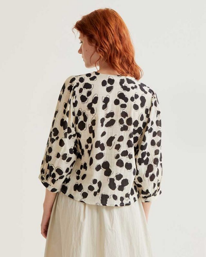Person wearing a leopard print blouse on a plain background
