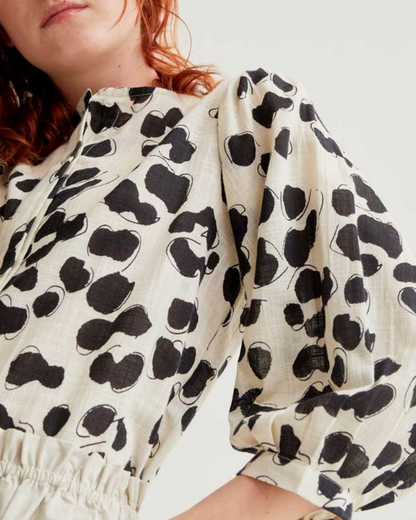 Person wearing a white dress with black abstract pattern on a plain background
