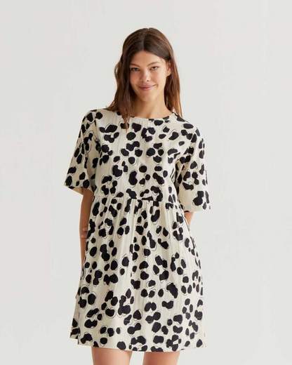 Woman wearing a black and white spot print dress on a light gray background