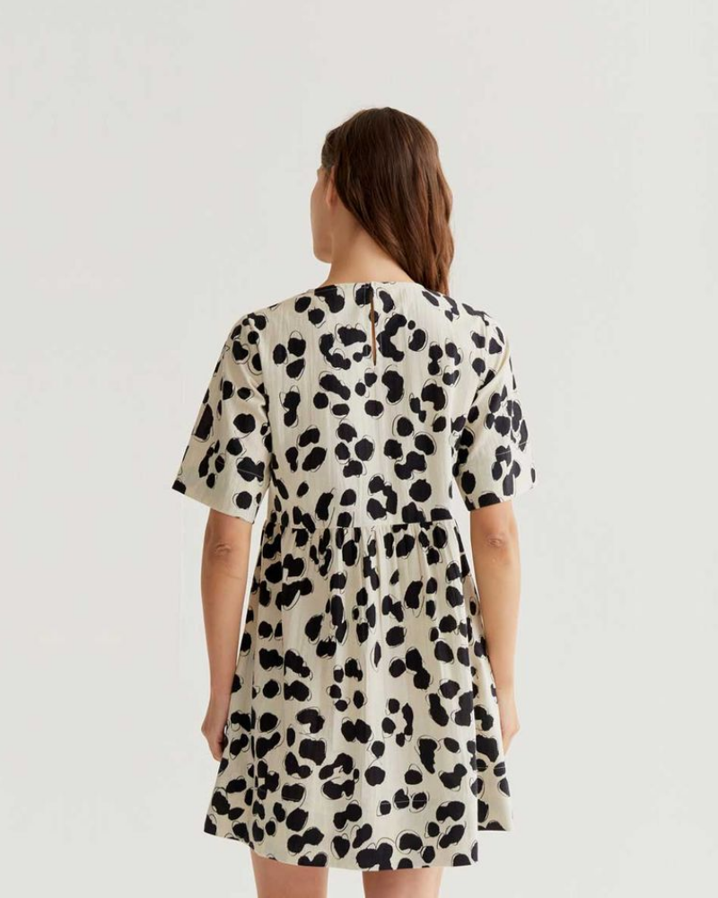 Woman wearing a spot print dress on a plain background