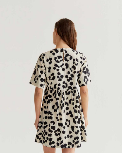 Woman wearing a spot print dress on a plain background