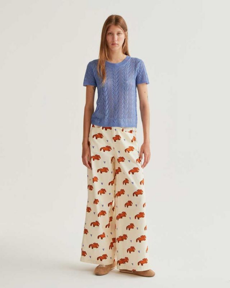 Woman wearing a blue top and patterned pants on a white background