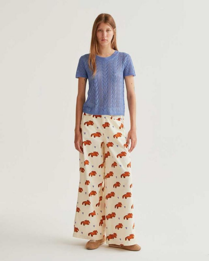 Woman wearing a blue top and patterned pants on a white background