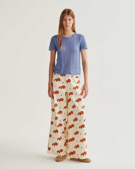 Woman wearing a blue top and patterned pants on a white background