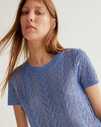 Woman wearing a blue knitted top against a plain background