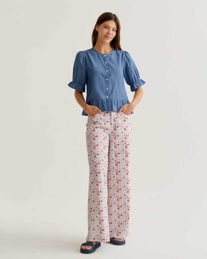 Woman wearing a blue top and floral pants on a white background