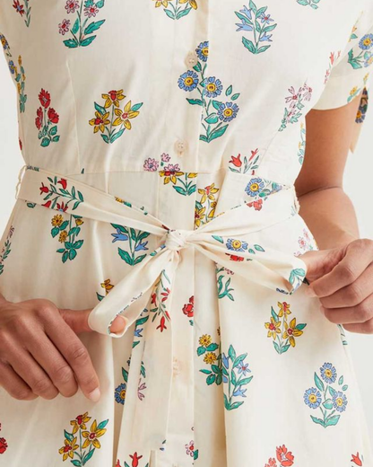 Close-up of a person wearing a floral dress with a tie waist.