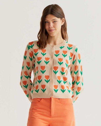 Woman wearing a cardigan with floral pattern and orange pants on a plain background