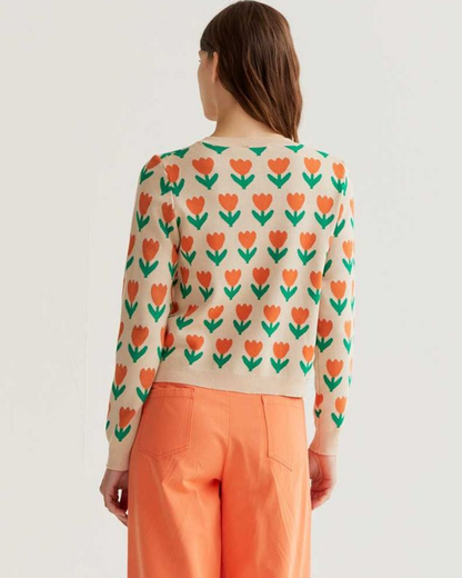 Woman wearing a sweater with a floral pattern and orange pants on a white background