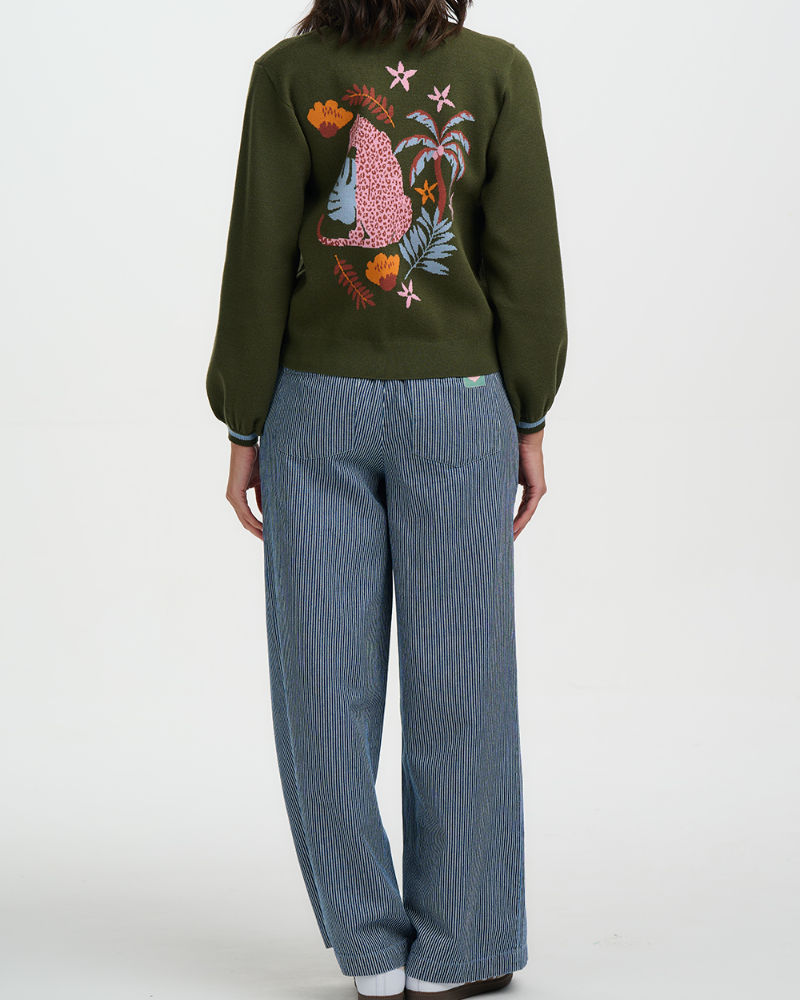 Person wearing a green sweater with a colorful design and blue pants on a white background