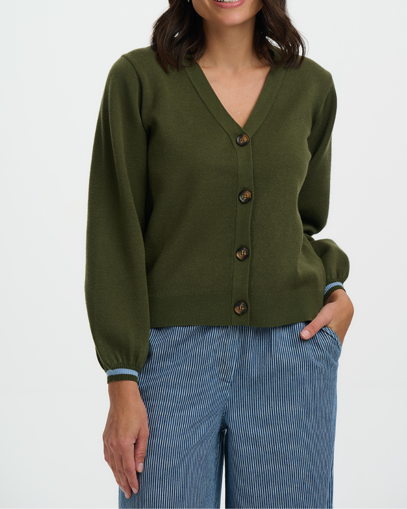 Person wearing a green cardigan with buttons on a white background