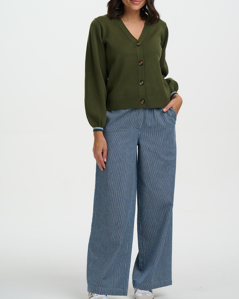 Person wearing an olive green cardigan and blue striped pants on a white background