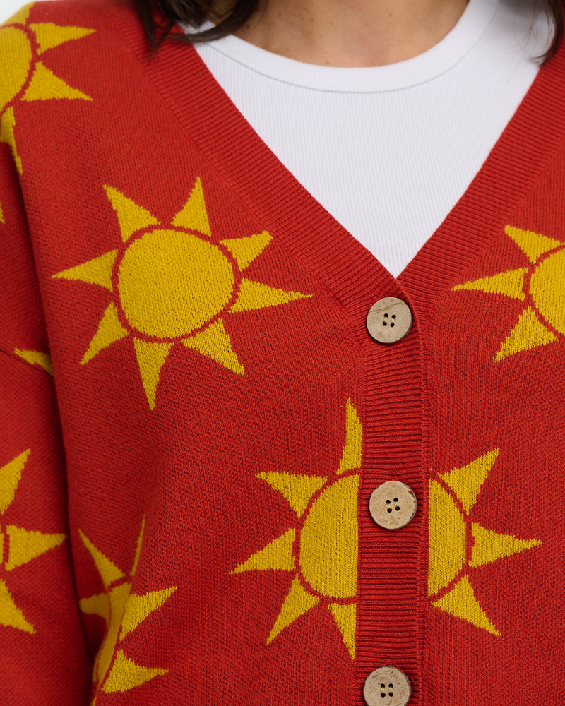 Red cardigan with yellow sun patterns worn by a person