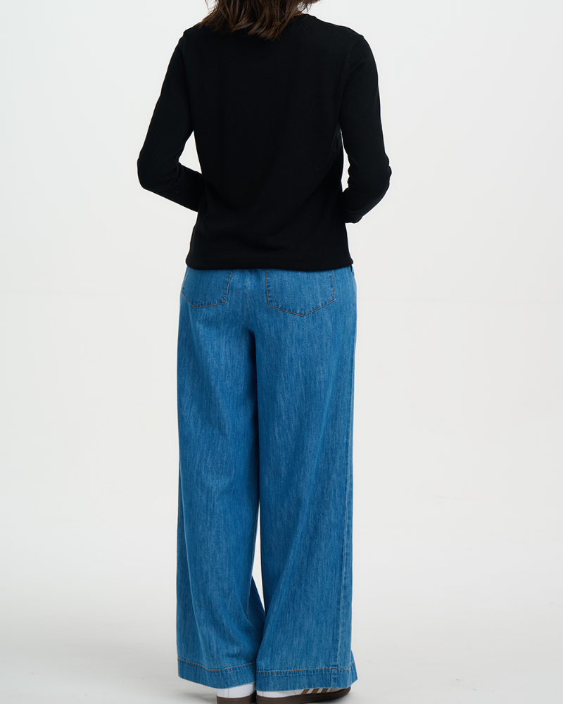 Person wearing a black top and blue jeans on a white background