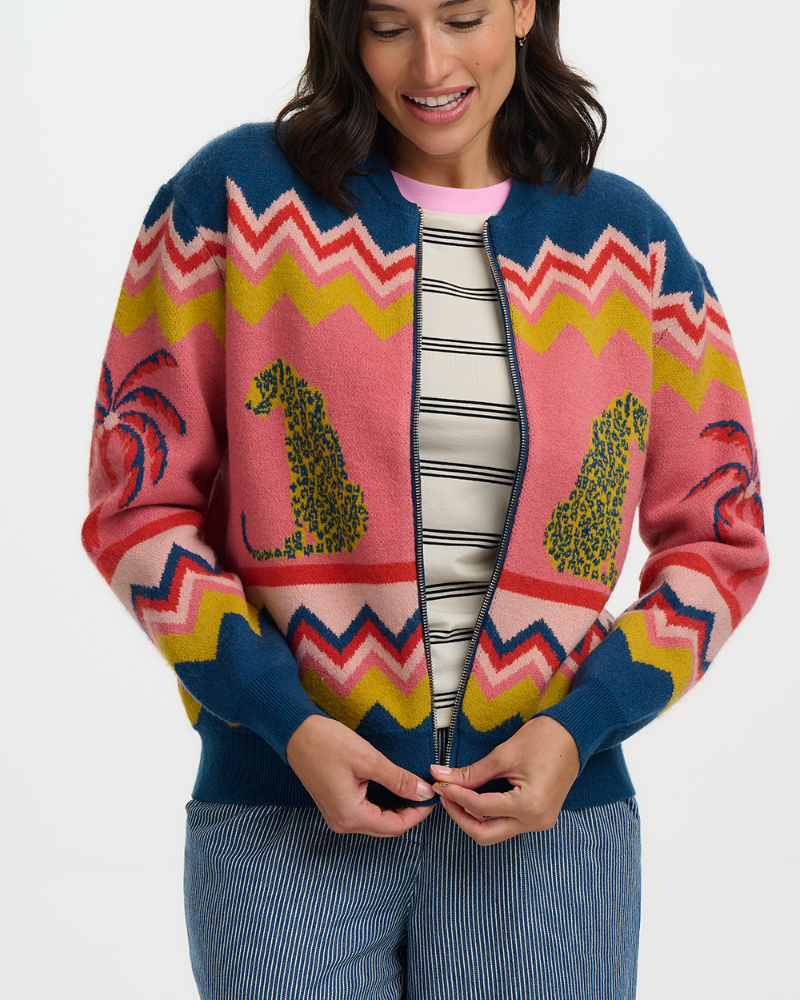 Woman wearing a colorful patterned cardigan with chevrons and animal designs on a white background