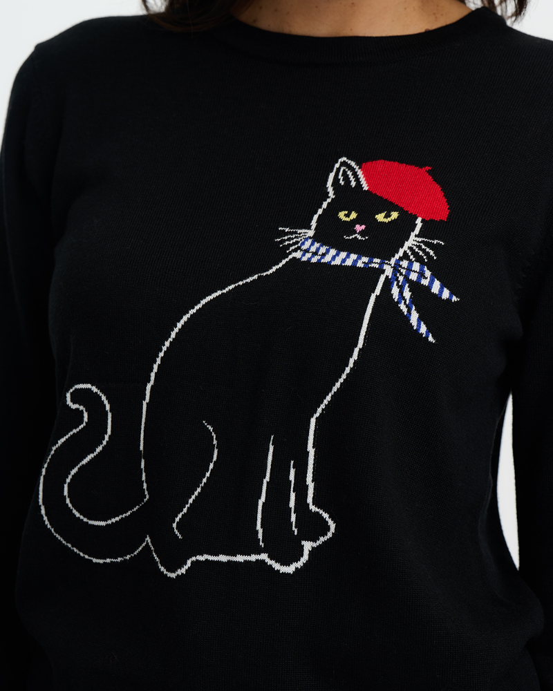 Black sweater with a cat wearing a red beret and blue scarf design.