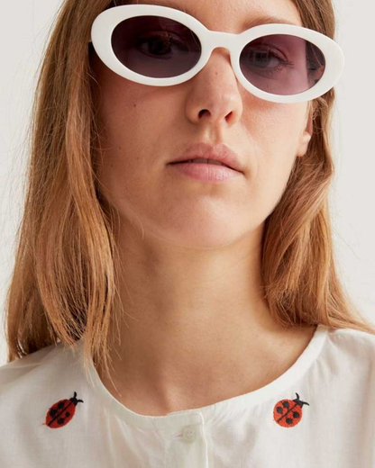 Person wearing white sunglasses with a plain background