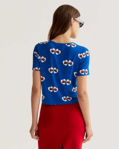Person wearing a blue top with a pattern and red pants on a white background