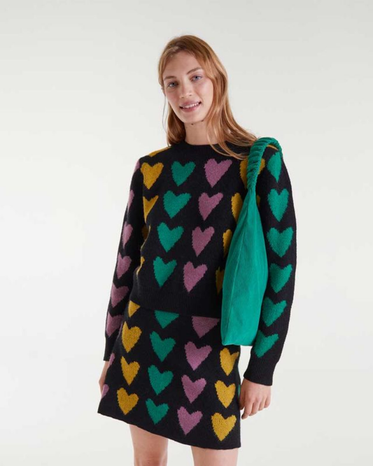 Woman wearing a black sweater with colorful heart pattern on a white background