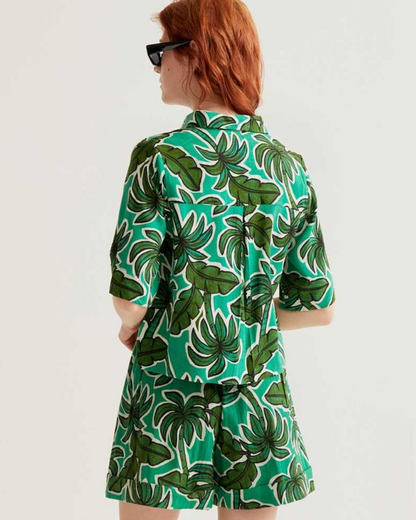 Person wearing a green leaf-patterned shirt on a white background