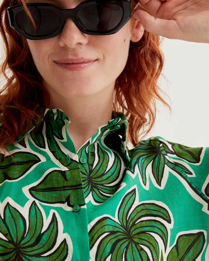 Person wearing a green leaf-patterned shirt with sunglasses on a white background