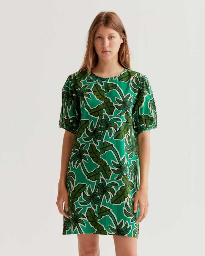 Woman wearing a green dress with leaf pattern on a white background