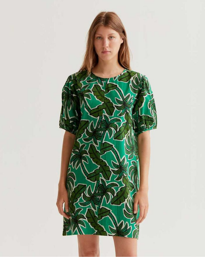 Woman wearing a green dress with leaf pattern on a white background