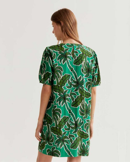 Woman wearing a green dress with leaf pattern on a white background
