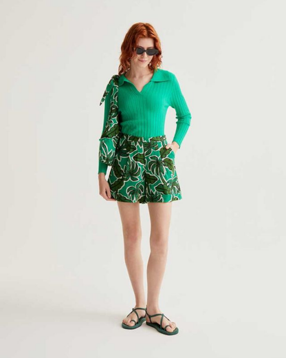 Person wearing a green outfit with a patterned skirt on a white background