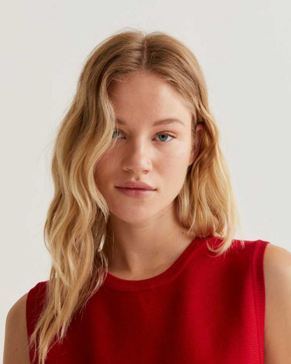 Woman with blonde hair wearing a red top against a plain background