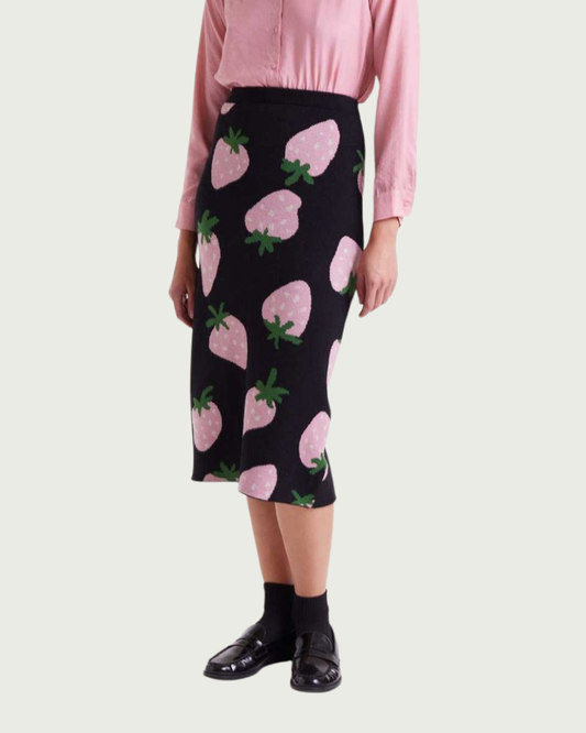 Person wearing a black skirt with pink strawberry pattern and a pink shirt.
