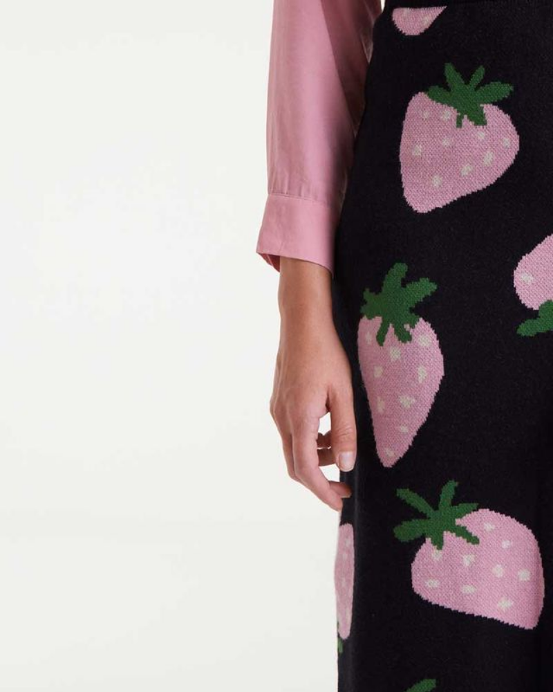 Black skirt with pink strawberry pattern worn by a person on a white background