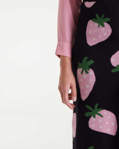 Black skirt with pink strawberry pattern worn by a person on a white background