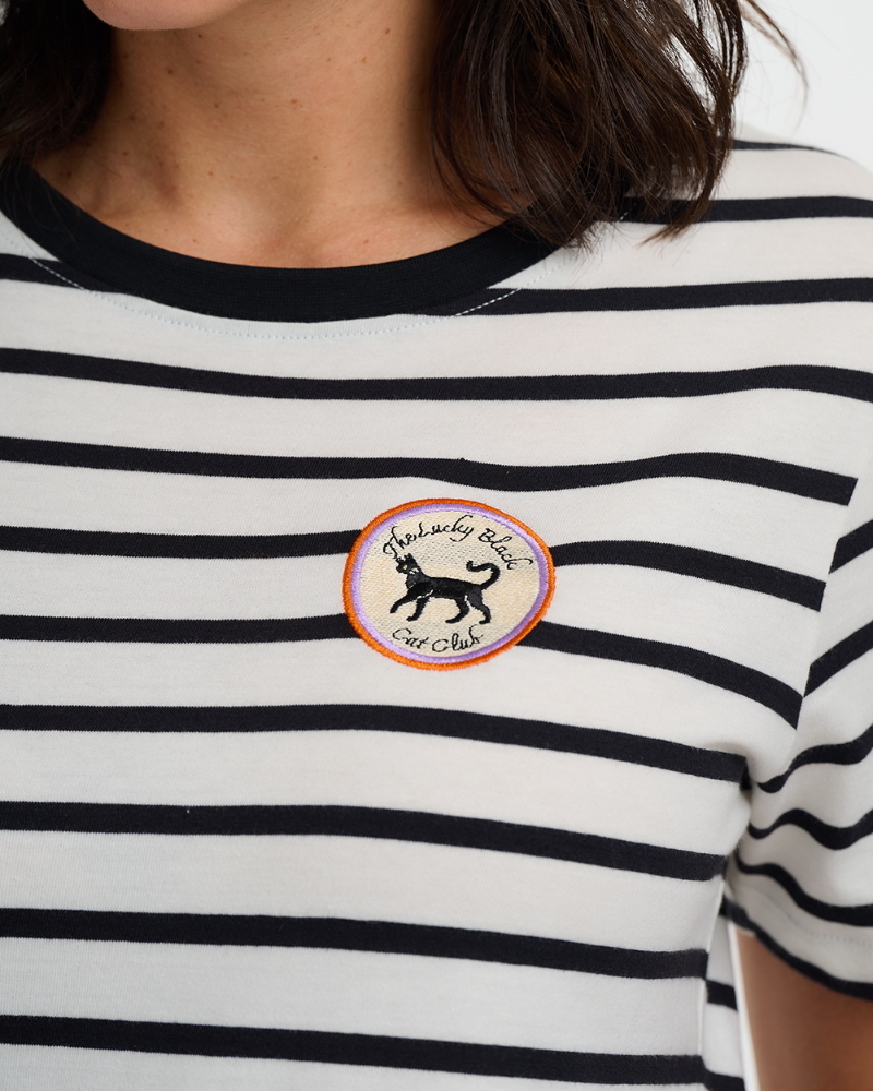 Person wearing a black and white striped shirt with a logo on the chest.